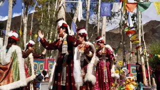 Auf dem Bild sieht man mehrere einheimische Frauen der Region Ladakh, die in traditioneller Kleidung tanzen.