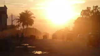 Eine Straße mit Palmen und Rikschas im Sonnenuntergang.