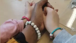 3 wrists are decorated with bracelets. In the middle is Joseline's hand, to the left and to the right are those of children.