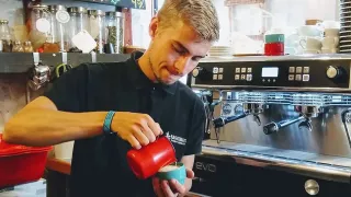 Sebastian vor einer Kaffeemaschine mit einer Kaffeetasse in der Hand.