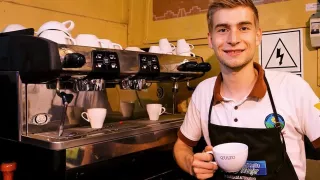 Sebastian vor einer Kaffeemaschine mit einer Kaffeetasse in der Hand.