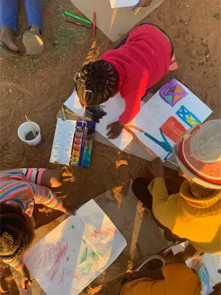 Eine Freiwillige malt mit Wasserfarben mit den Kinder aus dem Projekt ihrer Freiwilligenarbeit in Südafrika.