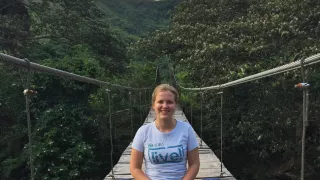 Melissa sitzt auf einer Hängebrücke, im Hintergrund ist der Regenwald Boliviens zu sehen, wo sie ihr fsj gemacht hat.
