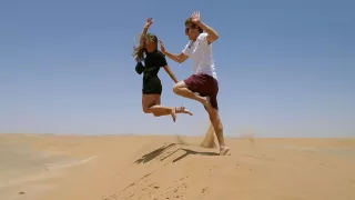 Eine Freiwillige und ein Freiwilliger springen in der Wüste in die Luft