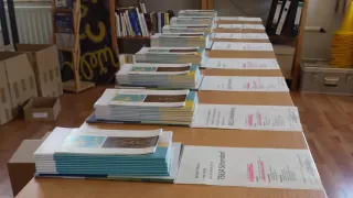 Several piles of brochures lying on a table in the library.