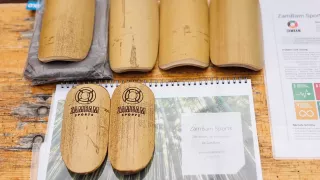 Sechs fertige Schienbeinschoner aus Bambus liegen auf einem Holztisch. Zwei davon haben bereits das eingravierte Logo von ZamBam Sports.