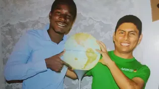 Arturo with a friend. Between them they are holding a lamp in the shape of a globe.