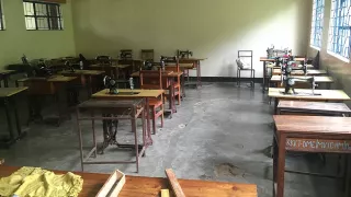 Zu sehen ist ein schlicht eingerichteter Klassenraum mit etwa 20 einfachen Nähtischen.