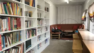 Ein Raum mit Regalen voller Büchern. Am Ende des Raumes steht ein Sofa.