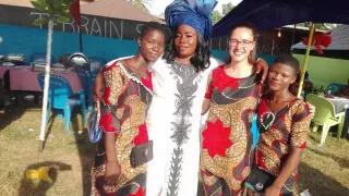 Hannah with three Beninese women. They are all wearing brightly coloured clothes and smiling at the camera.