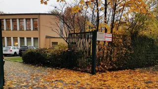 An open gate leading to Joseline's school. There are autumn leaves on the floor.
