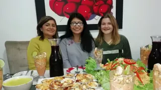 Lynnes Gastmutter, ihre Gastschwester und sie selbst sitzen an einem reich gedackten Essenstisch mit unterschiedlichen Speisen und Getränken