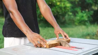 Nahaufnahme von Matteos Händen beim Sägen eines Holzstücks. Er machte seine Freiwilligenarbeit auf Sansibar  beim Practical Permaculture Institute Zanzibar.