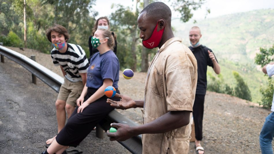 Ein Mann jongliert mit Bällen. Im Hintergrund schauen die Freiwilligen zu.