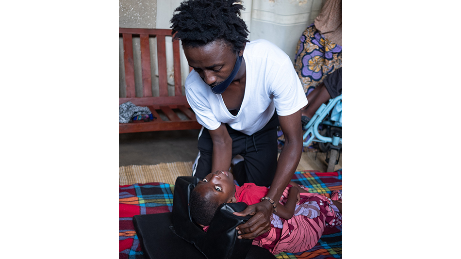Ein Mitarbeiter der Organisation "Love and Care" pflegt ein Kind und legt es behutsam auf ein Kissen