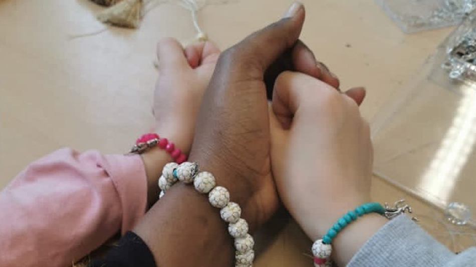 The photo shows three hands wearing selfmade colorful bracelets.