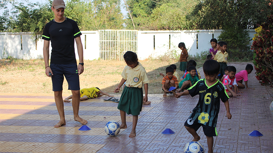 Un volontaire joue au football avec des enfants.