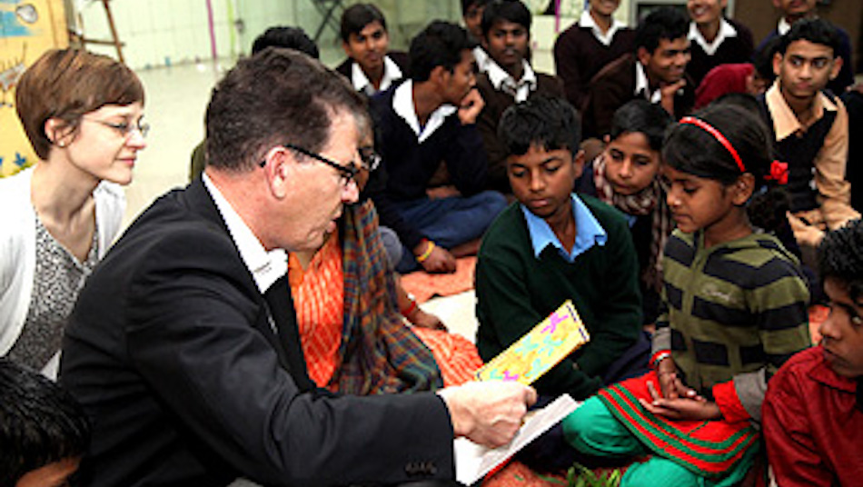 Der Minister sitzt zwischen den Kindern auf dem Boden